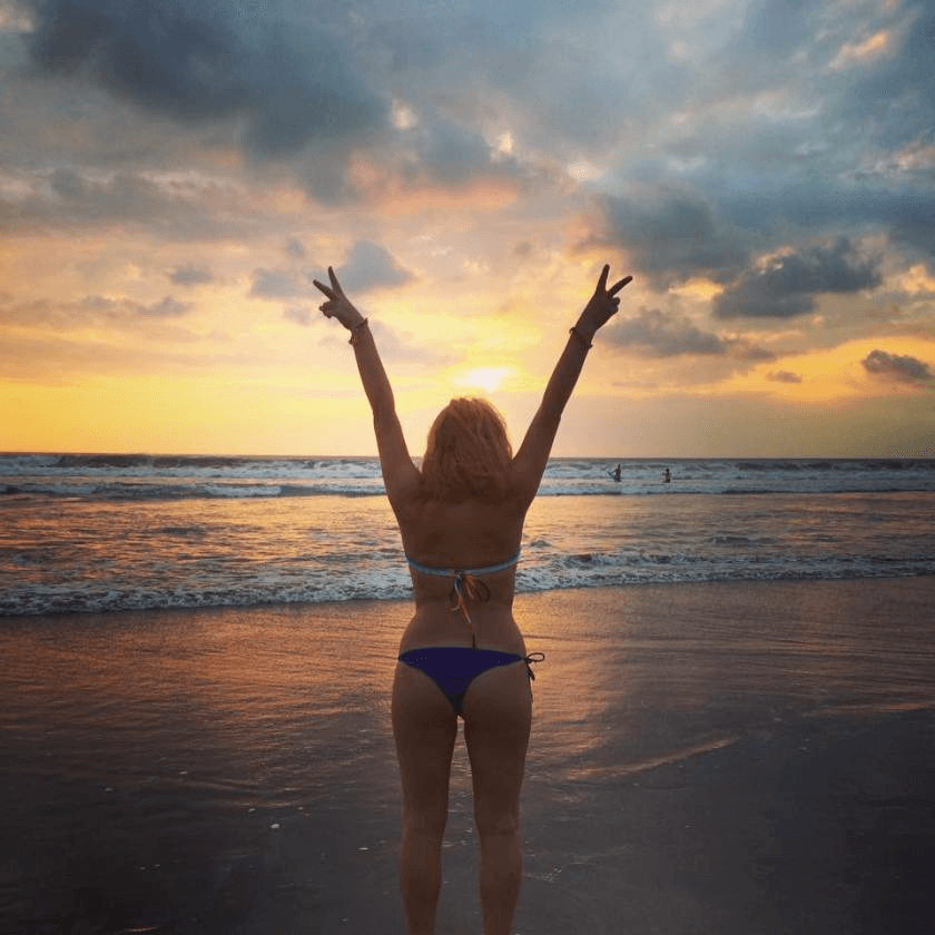 A girl in a bikini at the beach during sunset 