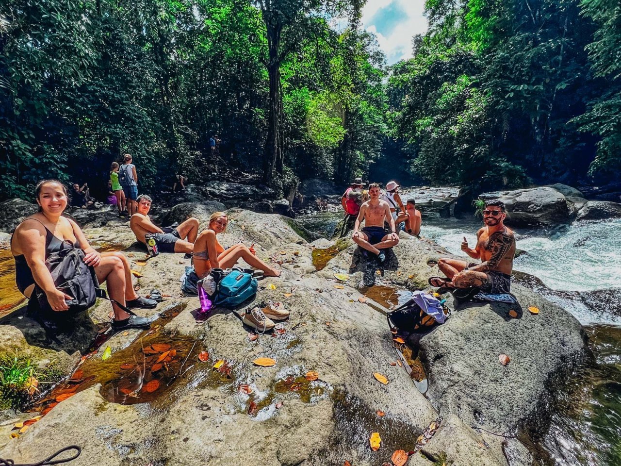 A group of people enjoying the sun by a waterfall.