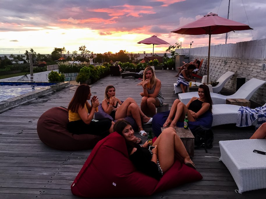 Group of travellers enjoying rooftoop sunset drinks by pool 