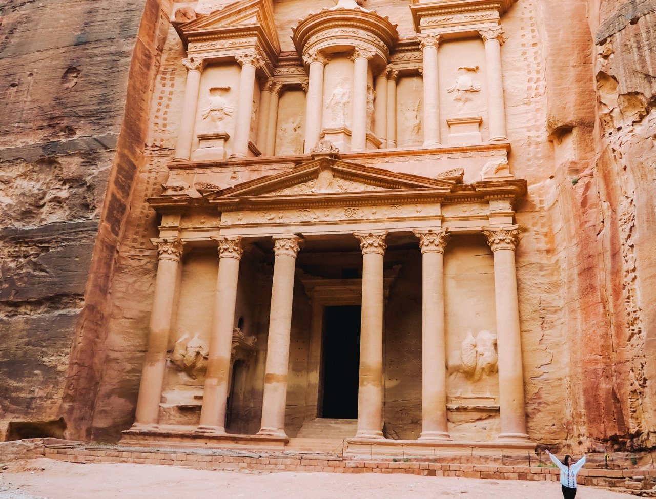 A young solo traveller posing in front of Petra in Jordan