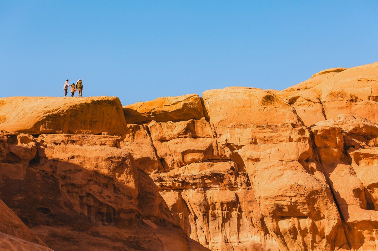 A group of young travellers on a TruTravels group tour in Jordan. They are standing at the top of a rock over looking the Wadi Rum desert.