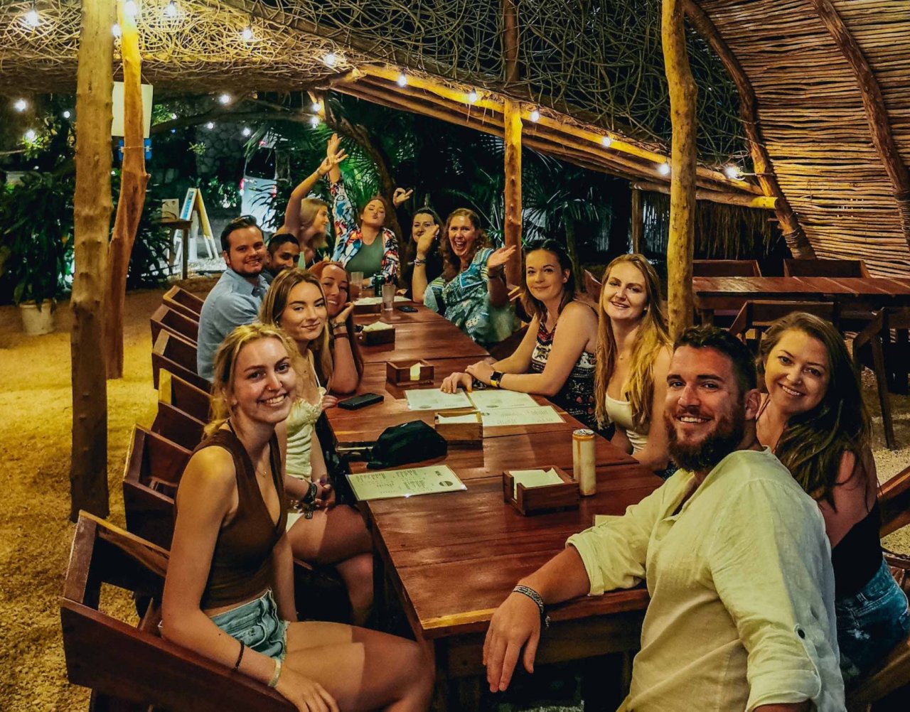 A large group of people smiling at a dinner table at night.