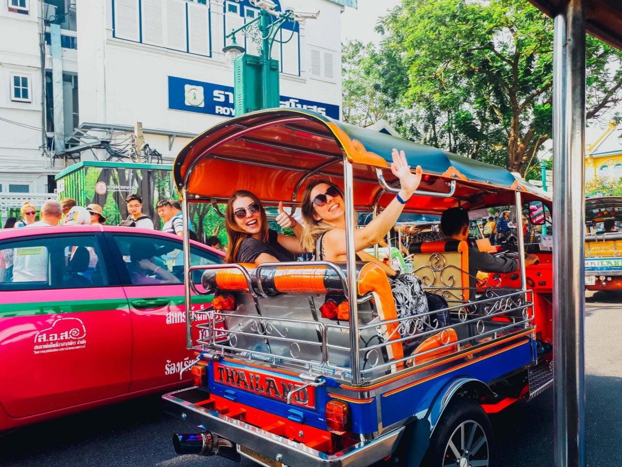 Two girls waving on a tuktuk in Bangkok